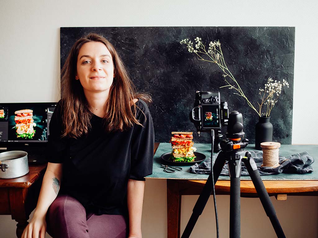 Portrait Charlie Cocotte dans son studio, devant une mise en scène de photographie culinaire