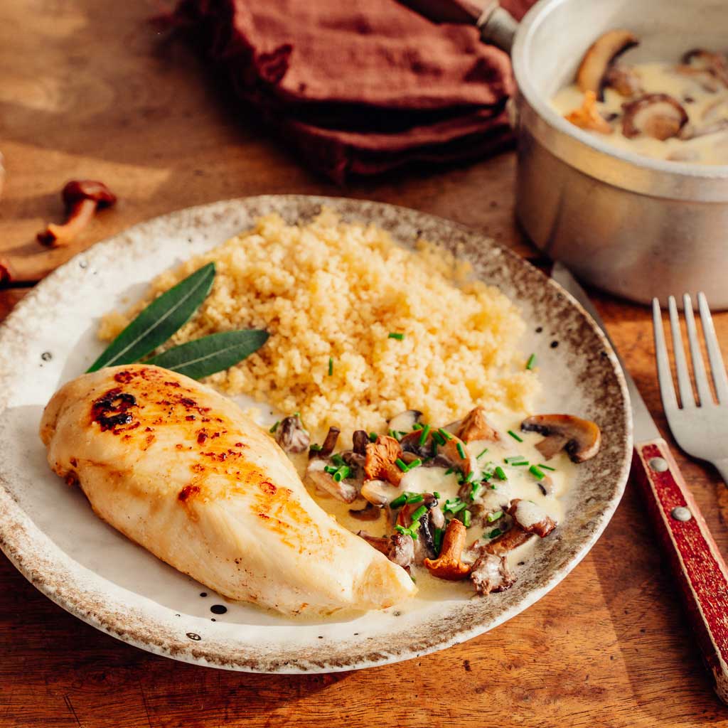 Photo d'une assiette de filet de poulet à l'étouffée avec sauce forestière et semoule